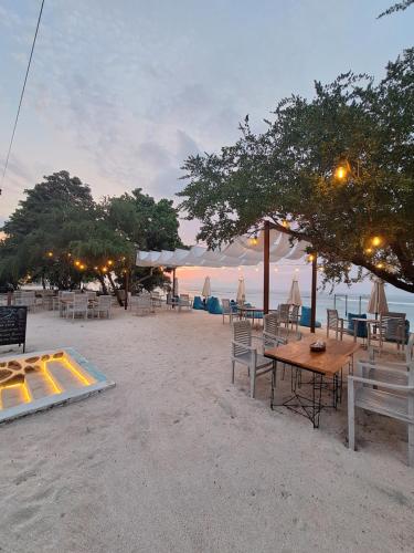 a table and chairs on a beach with the ocean at Taj Maza Sunset Villas in Gili Trawangan