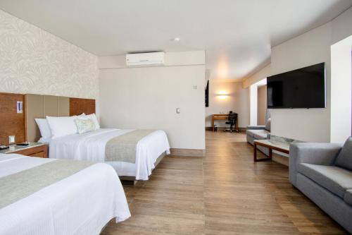 a hotel room with two beds and a flat screen tv at Hotel Plaza Diana in Guadalajara