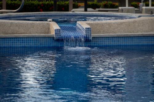 a swimming pool with a fountain in the water at Couples Condo B42 1BR Pool Jacuzzis Covered Terrace Walk to Ocean and Dining Secure Complex in Jacó
