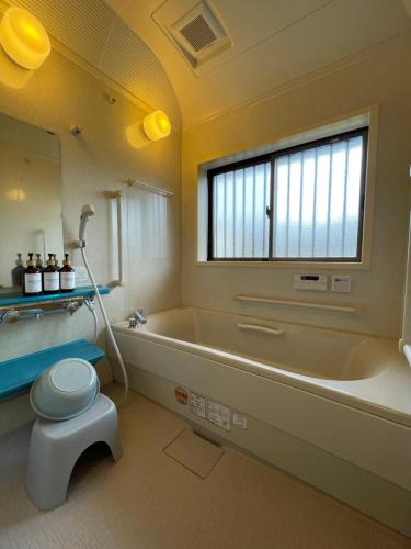 a bathroom with a tub and a toilet and a window at 貸切宿KUMANO in Miyazaki