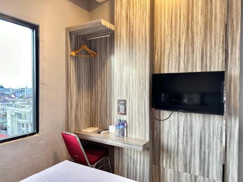 a room with a bed and a tv and a window at My Home Hotel Pontianak in Pontianak