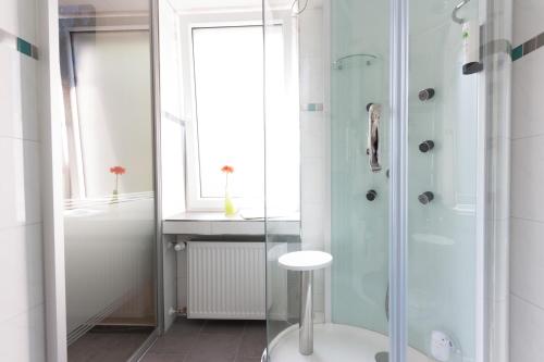 a bathroom with a glass shower and a stool at Stay-Inn Bielefeld Zentrum in Bielefeld