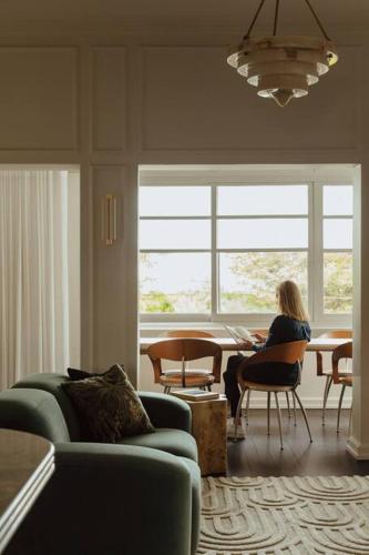 a woman sitting at a table in a living room at Tender is the Stay - Luxury designer 2BR Glenelg in Glenelg