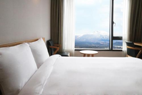 1 dormitorio con 1 cama y vistas a la montaña en Jeju Hotel the M, en Seogwipo
