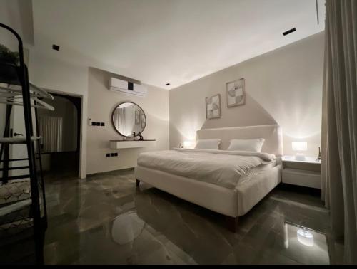 a white bedroom with a bed and a mirror at شقة جديدة بتصميم فاخر نظام مودرن in Riyadh
