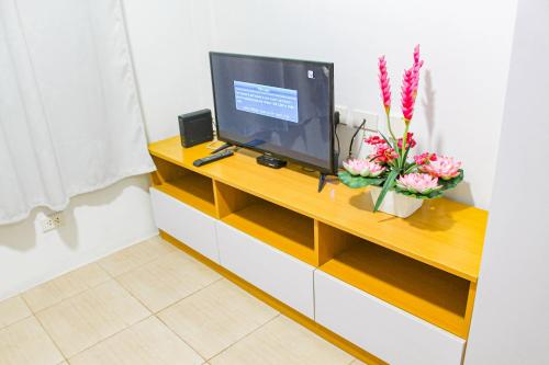 a television on a cabinet with flowers on it at Titan Condo at Studio City Tower 3 Alabang in Manila