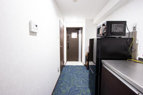 a kitchen with a microwave on top of a refrigerator at Hotel Fu-Rin in Fukuoka