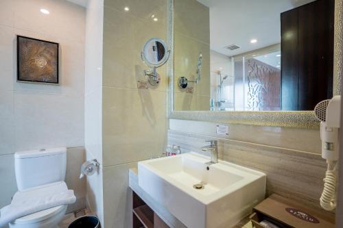 a bathroom with a sink and a toilet and a mirror at Belviu Hotel Bandung in Bandung