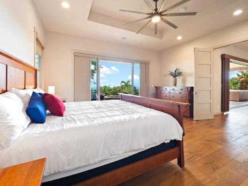 una camera con un grande letto e un ventilatore a soffitto di Kukui Hale at Makalei Estates a Kailua-Kona