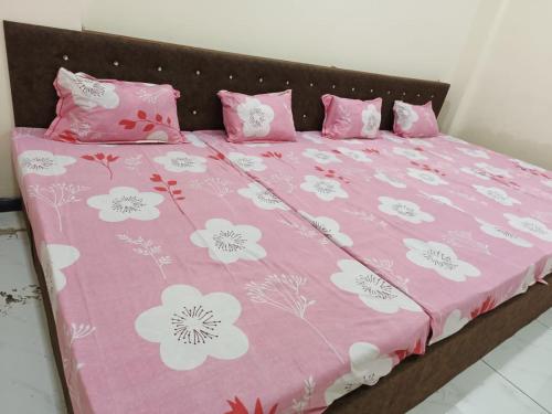 Una cama rosa con flores rosas y blancas. en Hanumant kripa geust house only for family, en Ujjain