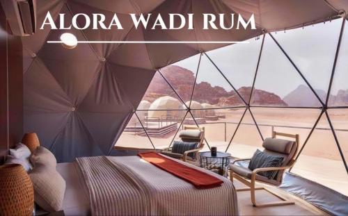 a bedroom with a bed and chairs in a tent at Alora Wadi Rum Luxury in Wadi Rum