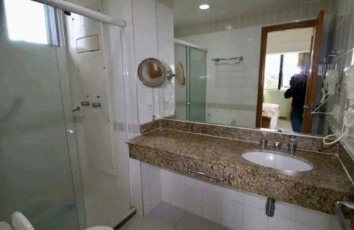 uma casa de banho com um lavatório, um chuveiro e um espelho. em Tropical Executive Hotel APT 606 em Manaus