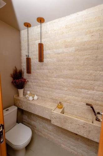 a bathroom with a toilet and a stone wall at Casa 19 da Vila Beija Flor in Mucugê