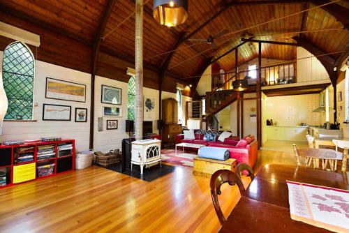 a living room with a red couch and a fireplace at Blue Gum Church in Beechworth