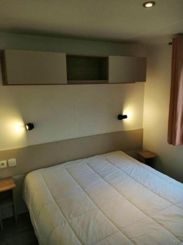 - un lit dans une chambre avec deux lumières sur le mur dans l'établissement Bungalow charmant à Condrieu avec piscine partagée conviviale, à Condrieu