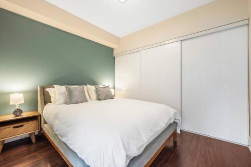 a bedroom with a white bed and a green wall at Deluxe CN Tower View FreeParking PrimeDT Location F1 in Toronto