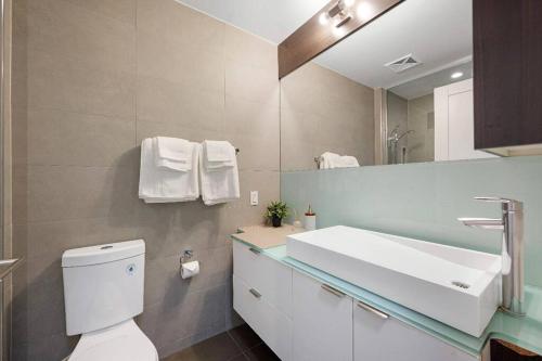 a bathroom with a toilet and a sink and a mirror at Deluxe CN Tower View FreeParking PrimeDT Location F1 in Toronto