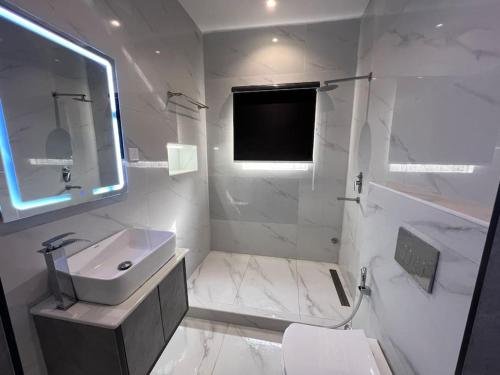 uma casa de banho branca com um lavatório e um espelho em Gorgeous 2 Bedroom with parking inside Banana Island, Ikoyi em Lagos