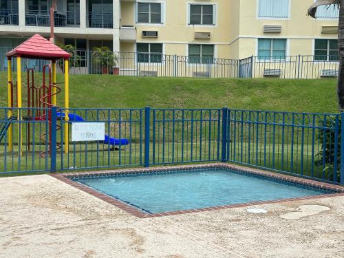 a small pool with a playground in front of a fence at La Costa View in Ceiba