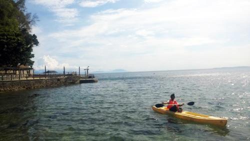 two people in a kayak in the water near a dock at Dive and Trek Resort and Marine Sanctuary in Bauan