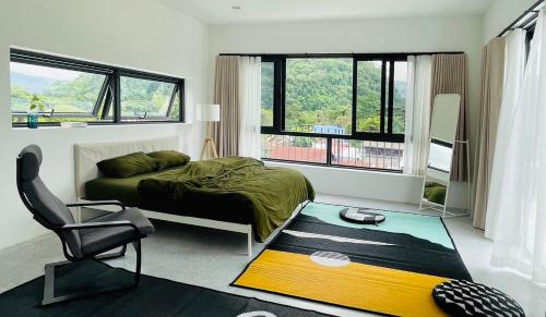 um quarto com uma cama, uma cadeira e janelas em ATATvilla Khaoyai with mountain rooftop view for party and BBQ em Mu Si