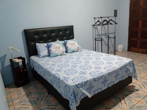 um quarto com uma cama com lençóis e almofadas azuis e brancas em Quarto familiar, aeroporto Guarulhos em Guarulhos