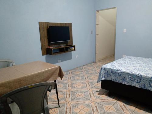 a bedroom with a bed and a tv on a wall at Quarto familiar, aeroporto Guarulhos in Guarulhos