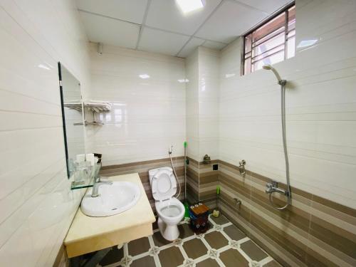 een badkamer met een toilet, een wastafel en een douche bij Kim Thoa Hotel Trung Khanh in Bản Piên