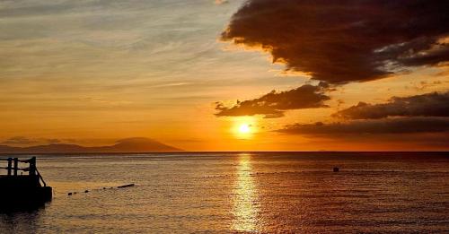 a sunset over the ocean with a boat in the water at Dive and Trek Resort and Marine Sanctuary in Bauan