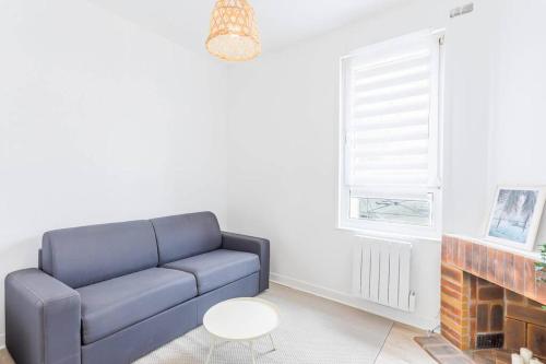 un salon avec un canapé bleu et une cheminée dans l'établissement Logement avec jardin 19min Paris, à Eaubonne