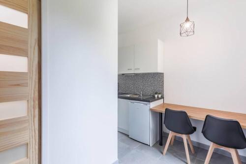 une cuisine avec deux chaises noires à côté d'un comptoir dans l'établissement Logement avec jardin 19min Paris, à Eaubonne