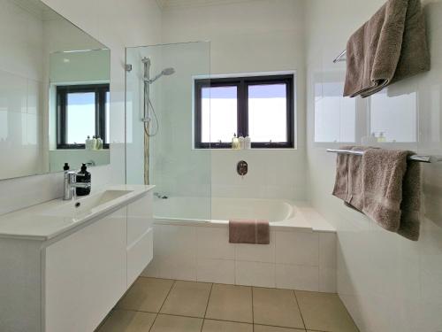 Baño blanco con bañera y lavamanos en The Mitchell Bondi Sun Terrace 2 en Sídney