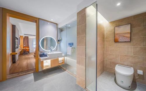 a bathroom with a toilet and a sink and a mirror at Vienna International Hotel Kunming longquan road Finance University in Kunming
