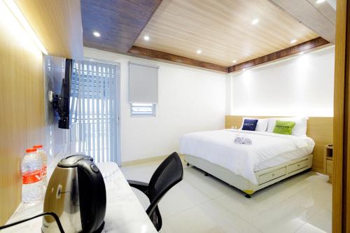 een slaapkamer met een bed, een bureau en een televisie bij Urbanview Hotel Kota Tua Jakarta in Jakarta