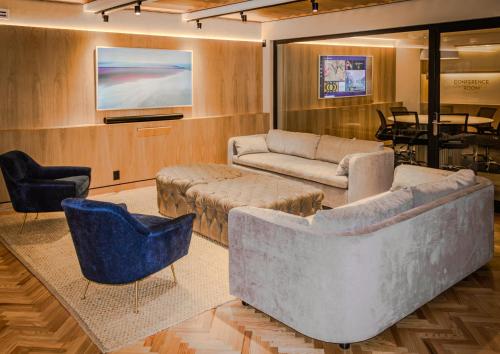 uma sala de estar com sofás e cadeiras e uma televisão em Ana Polanco Apartments em Cidade do México