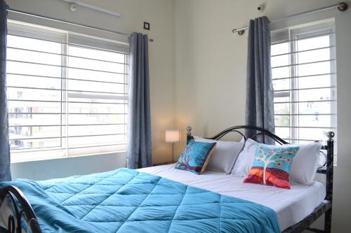 a bedroom with a bed with blue sheets and pillows at ILYA SERVICED APARTMENTS in Bangalore