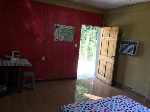 Cette chambre est dotée d'un mur rouge et d'une porte. dans l'établissement AmyRooms, à El Remate