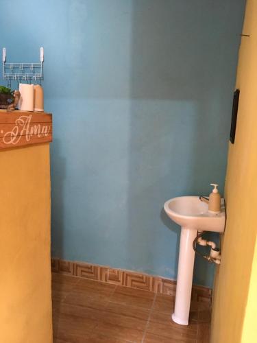 La salle de bains est pourvue d'un lavabo blanc et d'un mur bleu. dans l'établissement AmyRooms, à El Remate