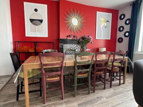 une salle à manger avec des murs rouges et une table et des chaises en bois dans l'établissement Gîte tout confort avec jardin, près de Valenciennes - 5 chambres, équipements bébé, borne électrique - FR-1-510-188, à Wallers