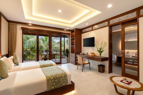 a bedroom with a bed and a desk and a television at Svarga Bebek Villas in Ubud