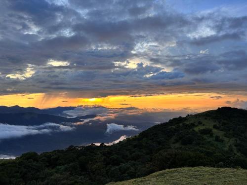una puesta de sol en la cima de una montaña con nubes en Coorg Cu’s Homestay, en Madikeri