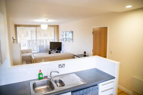 a kitchen with a sink and a living room at Leeds Vibrant 2 Bedroom Sleeps 4 in Leeds