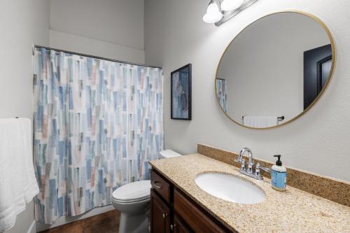 a bathroom with a sink and a toilet and a mirror at Art District Loft - 4BD/2BA Downtown SGF in Springfield