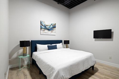 a bedroom with a bed and a tv on the wall at Art District Loft - 4BD/2BA Downtown SGF in Springfield