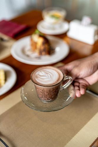a person holding a cup of coffee on a table at Svarga Bebek Villas in Ubud