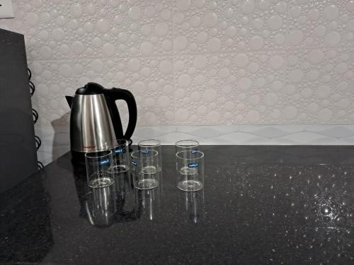 a coffee pot and four empty glasses on a counter at Galeela Plaza in Tāmarakulam