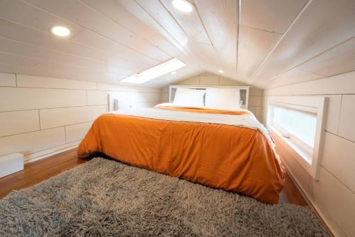 Un dormitorio con una cama naranja en una habitación pequeña. en Teal Tiny Home Creek Views, en San Luis Obispo