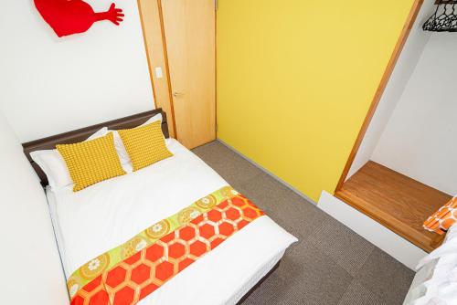 a bedroom with a bed with yellow and orange pillows at 両国駅前 in Tokyo