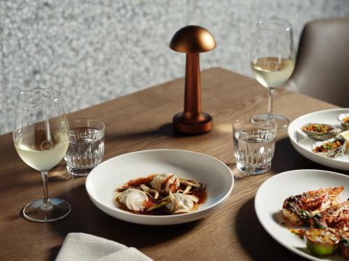 a wooden table with plates of food and glasses of wine at Ardo in Townsville
