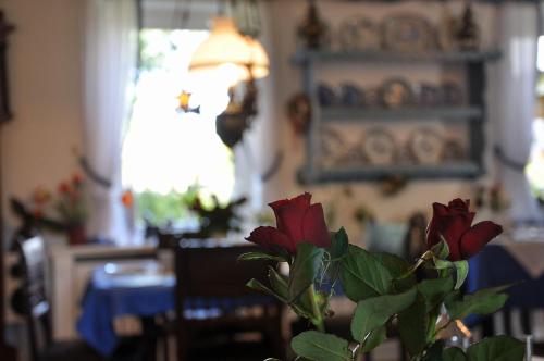 a vase with red flowers in a dining room at Inselhotel Arfsten in Wyk auf Föhr